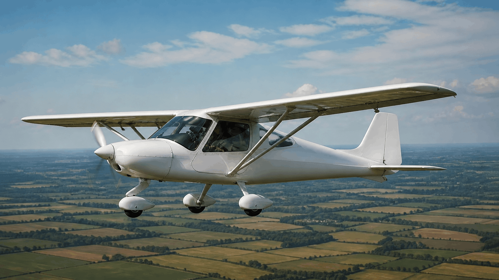 Ikarus C42-style light aircraft cruising above rural farmland