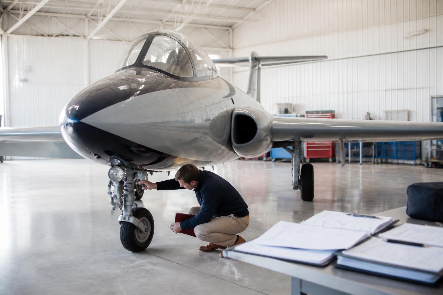 Specialist inspecting records and landing gear on a classic trainer jet